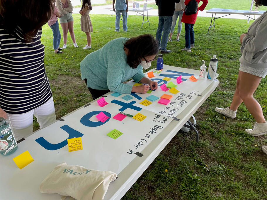 An attendee adds to our mural that asks: "What does supporting people of color in Newton look like to you?"